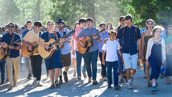 Campers walking with guitars and singing